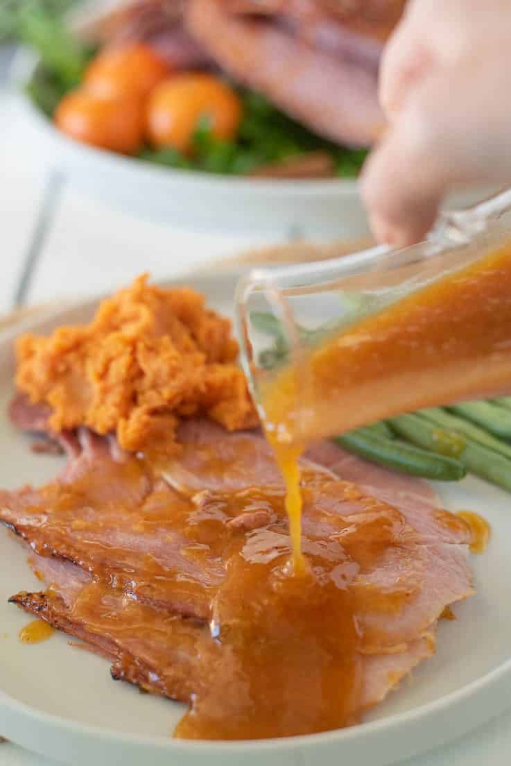 Mandarin orange glaze being drizzled over slices of ham