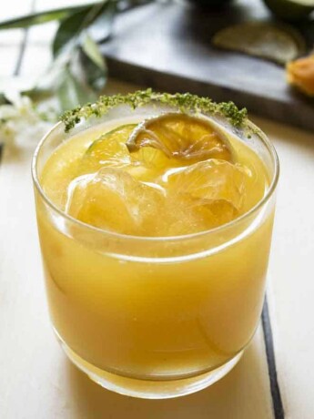 A glass of mango juice with ice and lime slices