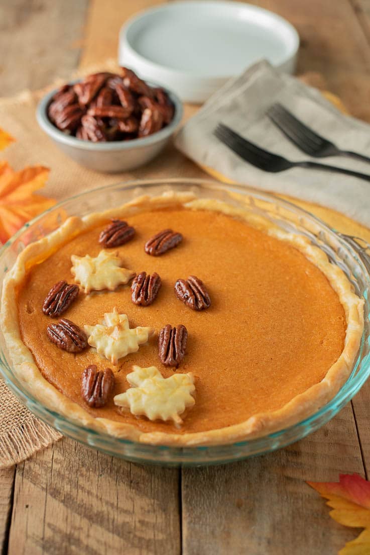 Maple Sweet Potato Pie in a glass pie pan garnished with pastry maple leaves and maple glazed pecans