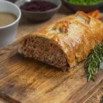 Half of a meatloaf wrapped in puff pastry on a board