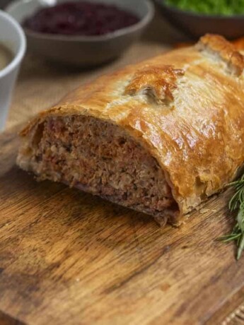 Half of a meatloaf wrapped in puff pastry on a board