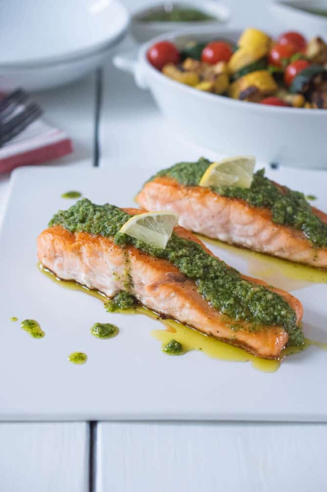 2 pieces of salmon drizzled with pesto and garnished with lemon pieces