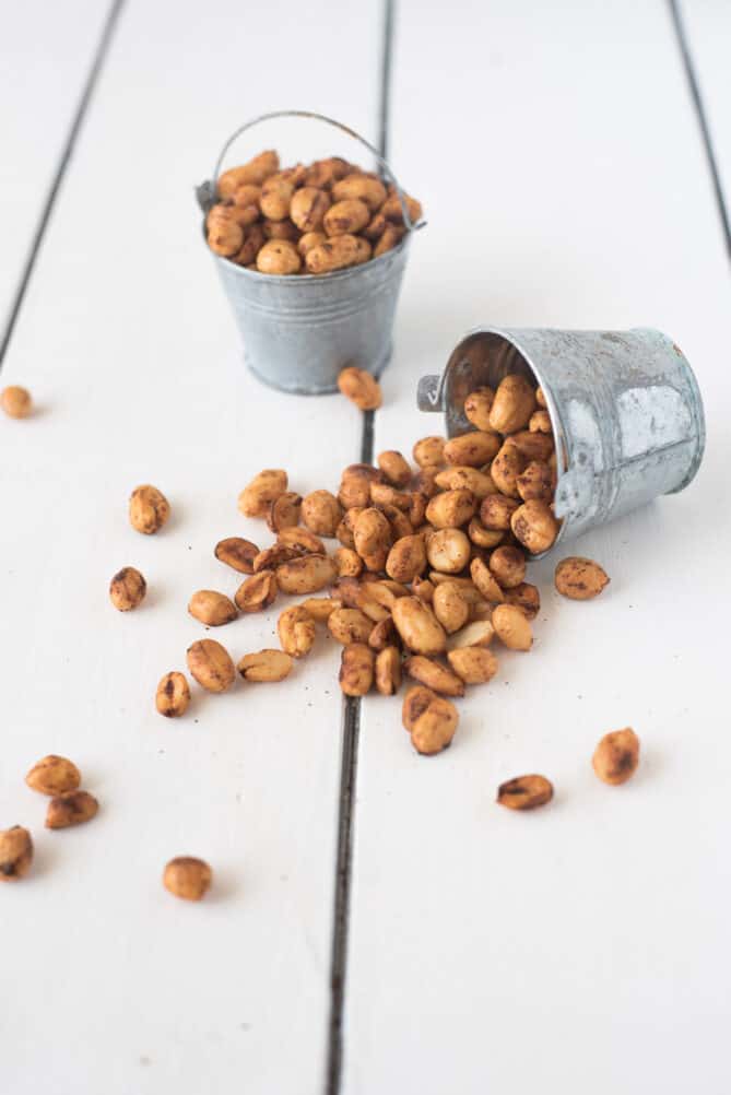 Peanuts coated with spices spilling out of a mini bucket