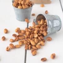A small silver bucket filled with peanuts that has fallen over