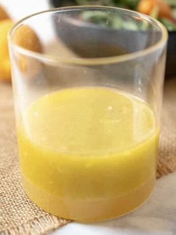 Meyer lemon marinade and dressing in a glass container with a salad