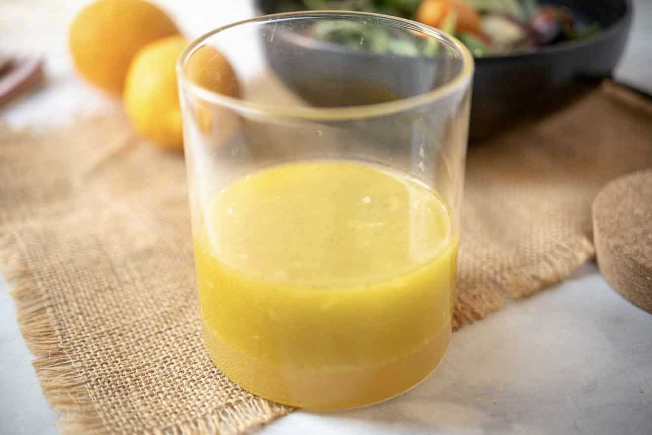 Meyer lemon marinade and dressing in a glass container with a salad