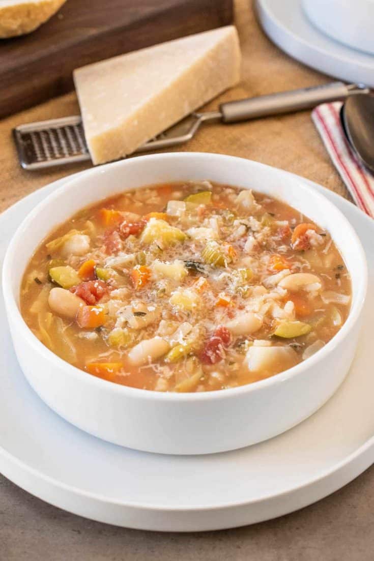 A white bowl filled with minestrone soup with beans and vegetables
