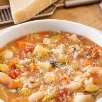 A hearty minestrone soup topped with melting Parmesan cheese