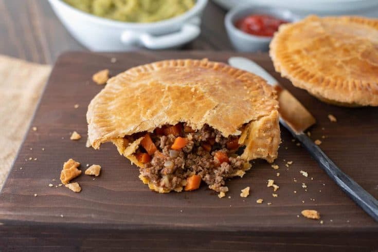A cut open minced beef and onion pie with flaky pastry, beef, onion and carrot filling