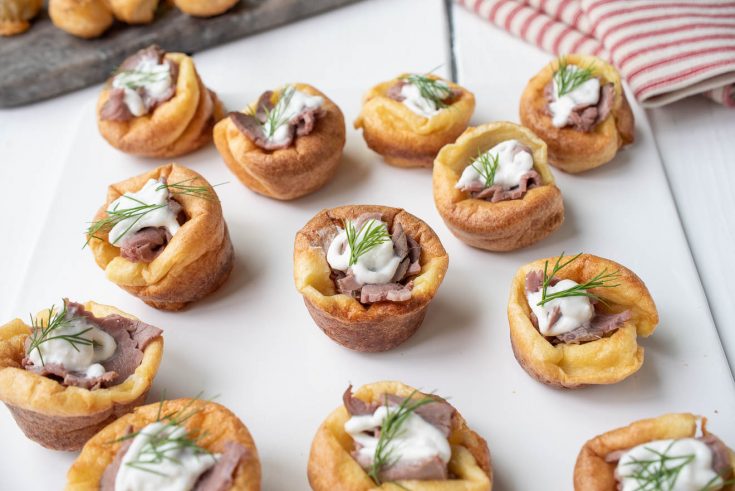 Golden brown mini Yorkshire puddings are filled with sliced roast beef and horseradish sauce