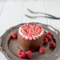 Mini chocolate cake for two on a grey plate with fresh raspberries