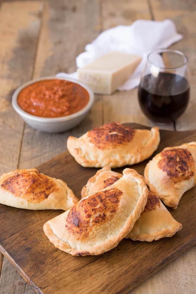 Mini ham and cheese calzones on a board with marinara sauce
