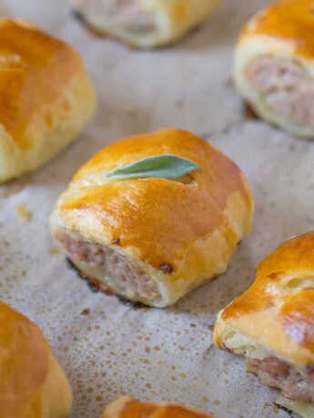Small pork sausage rolls on a baking tray