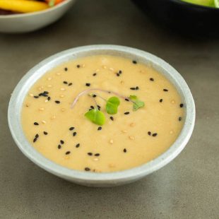 Miso dressing in a bowl garnished with black and white sesame seeds