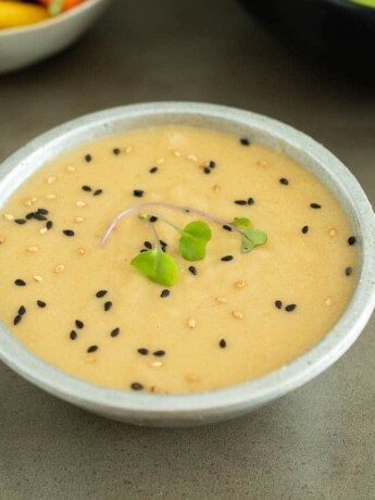 Miso dressing in a bowl garnished with black and white sesame seeds