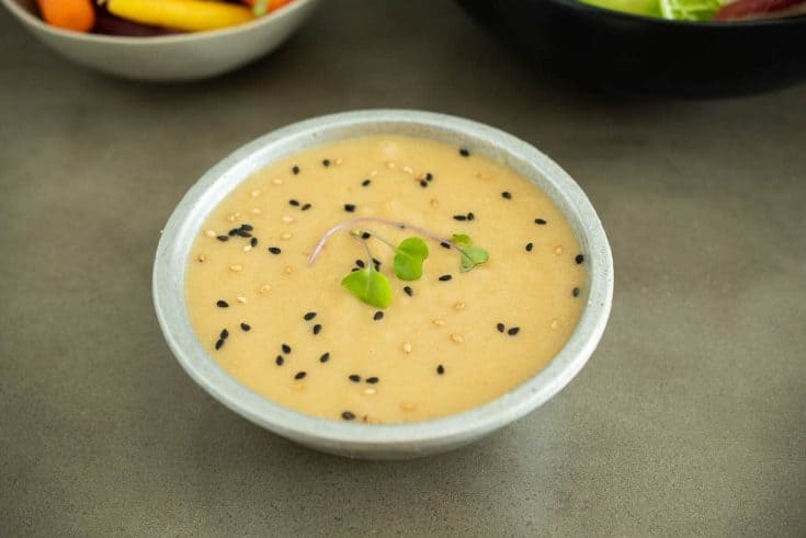 Miso dressing in a bowl garnished with black and white sesame seeds