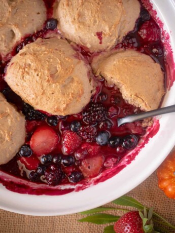 Spooning fruit cobbler out of a white bowl