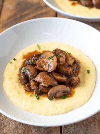 Creamy polenta is served topped with meaty mushroom pancetta ragu
