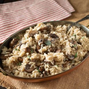 A copper serving dish full of mushroom and sage rice pilaf