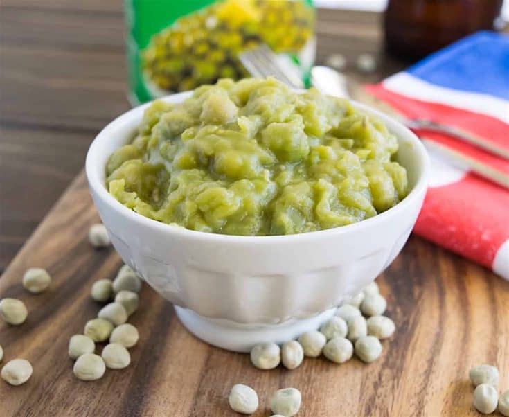 Vibrant green mushy peas in a white bowl