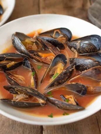 A large bowl of mussels in tomato broth with grilled bread
