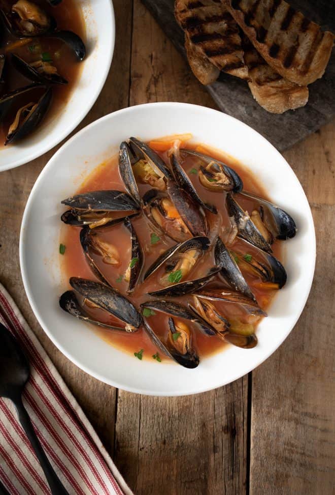 A bowl of mussel soup with crusty bread