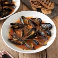 Mussel Soup in a white bowl served with grilled bread