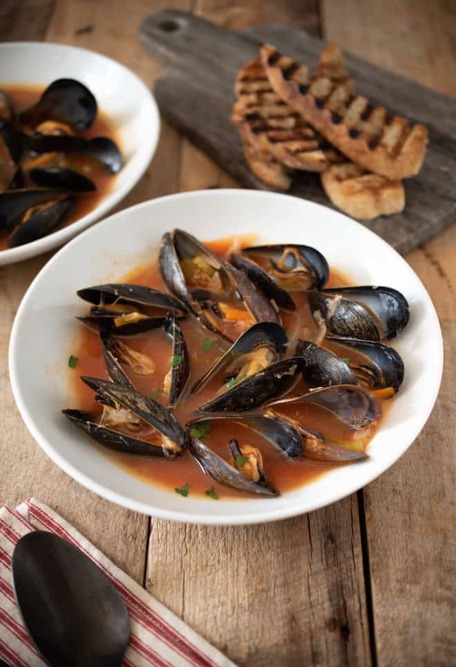 Mussel Soup in a white bowl served with grilled bread