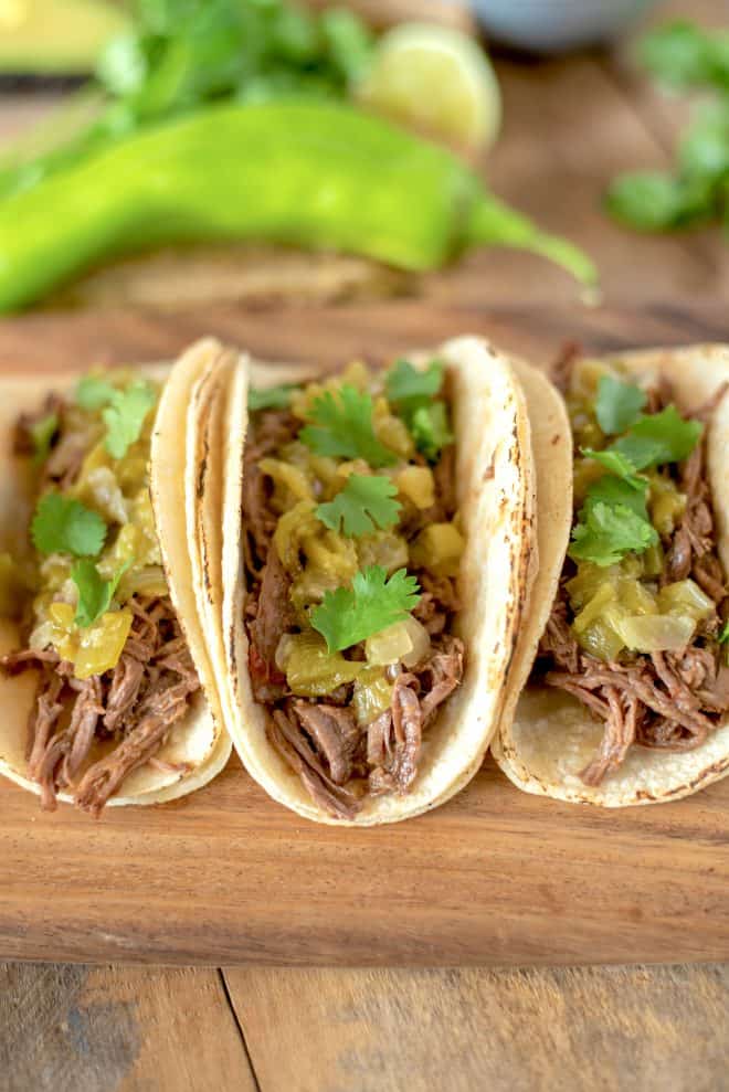 Shredded Beef Tacos topped with hatch green chile sauce and cilantro