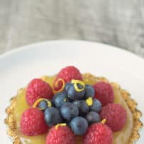 A small lemon tart topped with raspberries and blueberries
