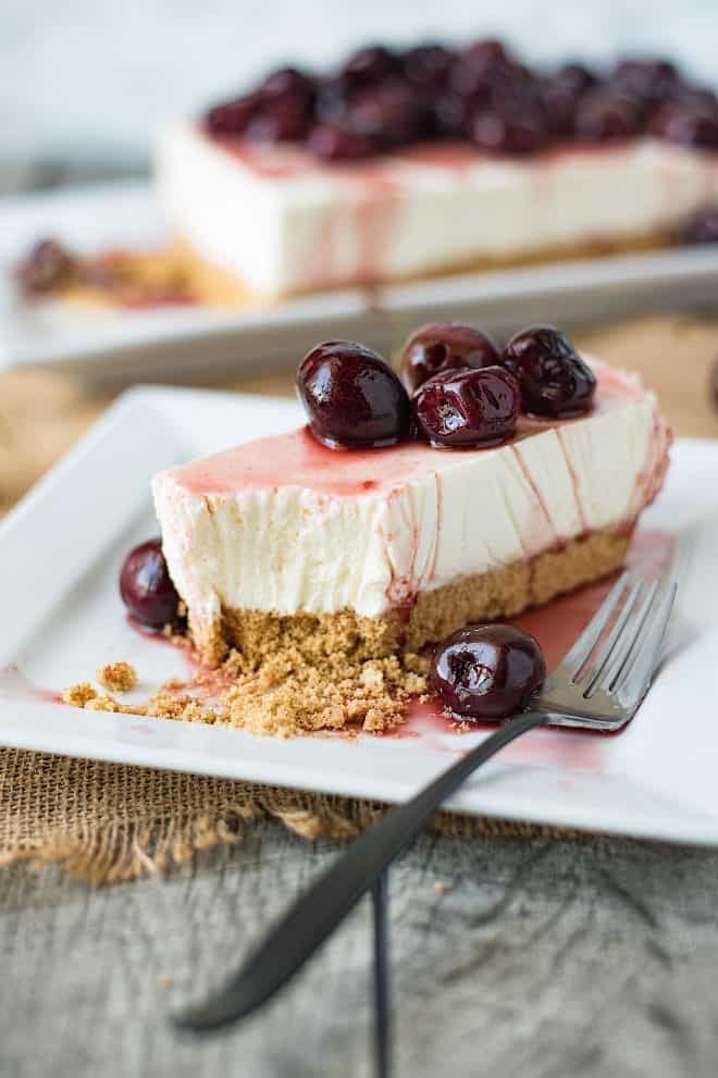 A slice of no bake cherry lemon cheesecake on a white plate with a fork