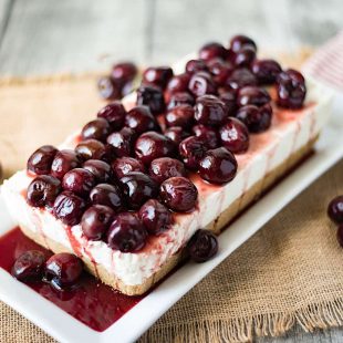 A rectangle shaped no bake cherry cheesecake topped with whole fresh cherries