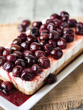 A rectangle shaped no bake cherry cheesecake topped with whole fresh cherries
