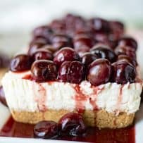 Cherry cheesecake from the side showing the Graham cracker crust and juicy cherry topping