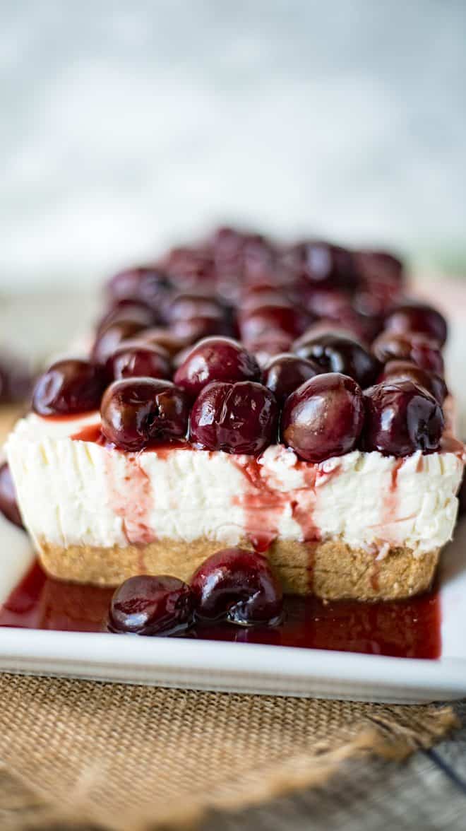 Cherry cheesecake from the side showing the Graham cracker crust and juicy cherry topping