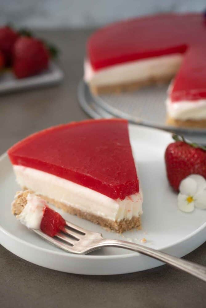 A slice of strawberry topped cheesecake on a plate