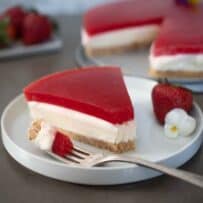 A slice of cheesecake topped with a strawberry jello/jello layer