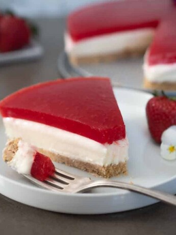 A slice of cheesecake topped with a strawberry jello/jello layer