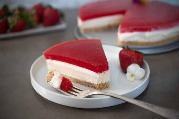 A slice of cheesecake topped with a strawberry jello/jello layer