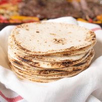 Charred flour tortillas stacked and ready to make tacos