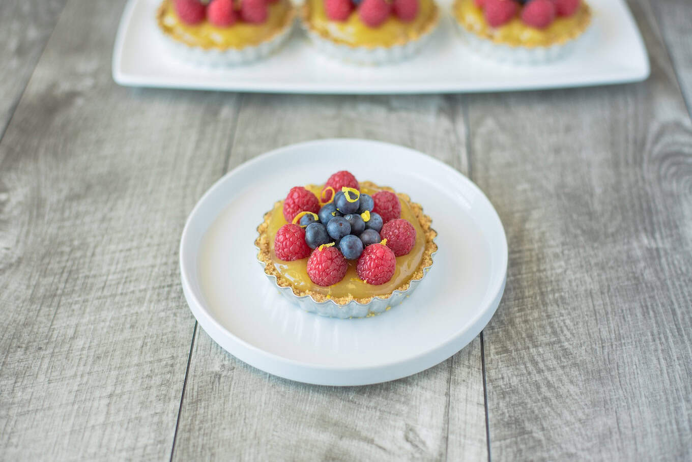 A small tart filled with orange custard topped with berrie