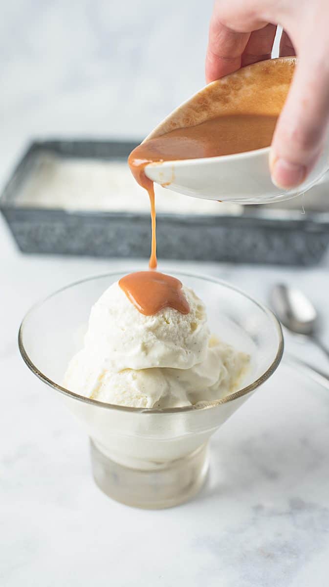 Caramel sauce being poured over the vanilla ice cream
