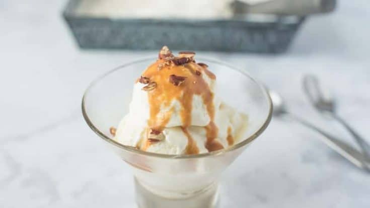 No churn vanilla bean ice cream in a round glass bowl with caramel and pecans