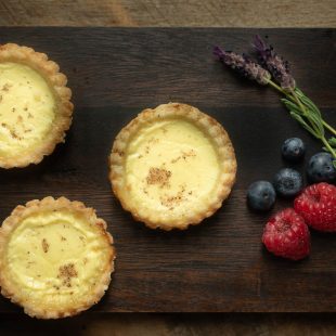 3 small egg custard tarts with raspberries, blueberries and fresh lavender flowers