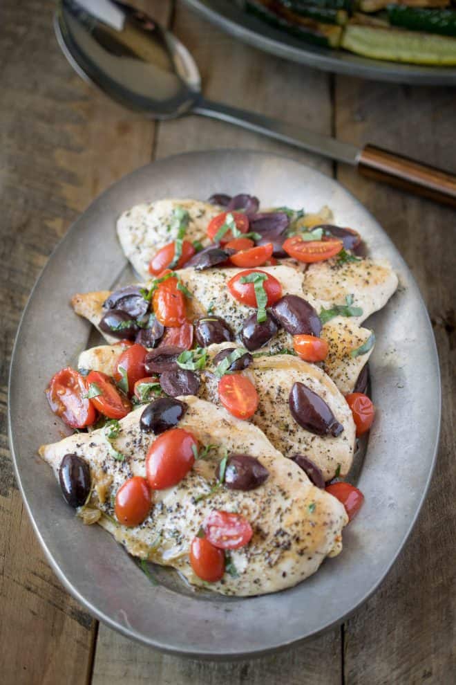 One pan chicken with tomatoes and olives on a silver serving platter