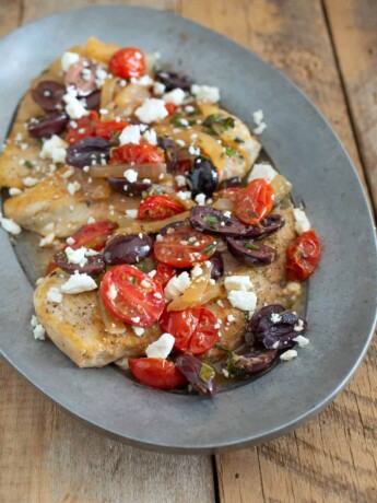 A closeup showing the chicken topped with tomatoes, olives and feta cheese