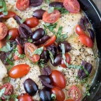 Cherry tomatoes and Kalamata olives on top of chicken breasts with fresh basil