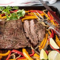 Sliced beef on a sheet pan with onions and peppers