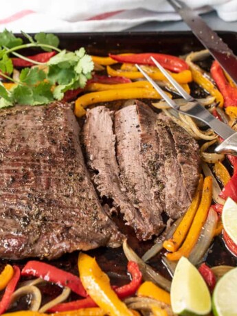 Sliced beef on a sheet pan with onions and peppers