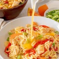 Orzo chicken salad being dressed with orange dressing